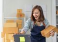 Young woman happily processing online orders in a home office.