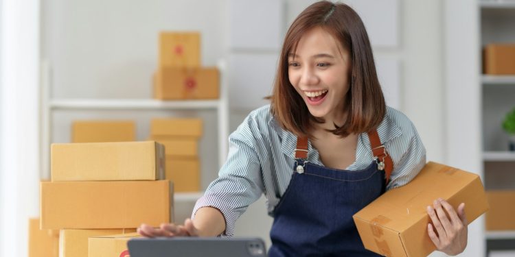 Young woman happily processing online orders in a home office.